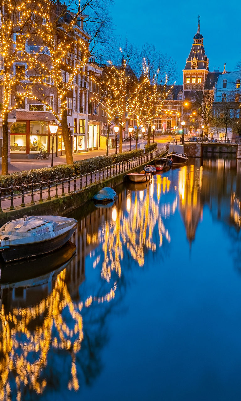 Illuminated canal in Amsterdam at dusk