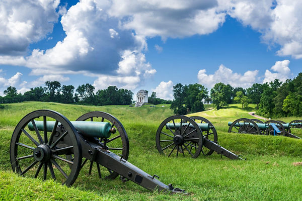 Historic cannons on grassy battlefield under blue sky