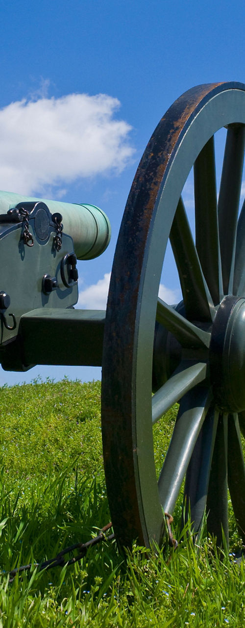 Historic cannon on grassy hill under blue sky