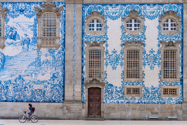Cyclist passing ornate blue tile facade