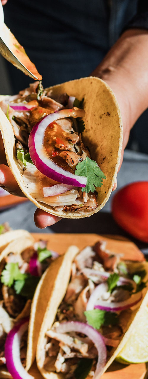 Person assembling tacos with fresh ingredients