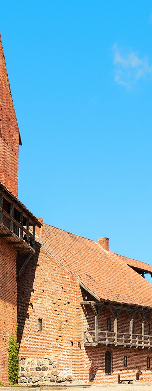 Historic red brick castle with round tower under blue sky