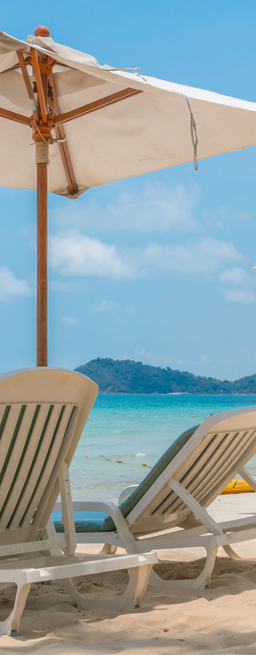 Empty lounge chairs under umbrellas on tropical beach