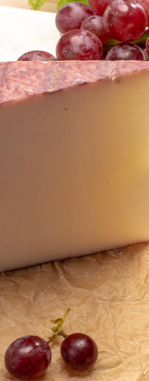 Cheese wedge with grapes on wooden board