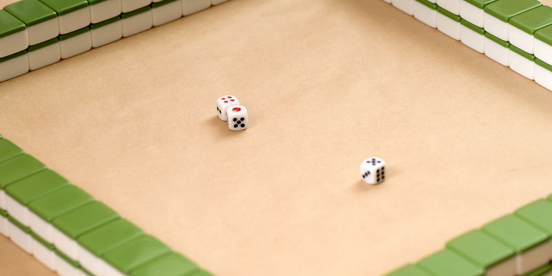 Mahjong tiles and dice on beige surface