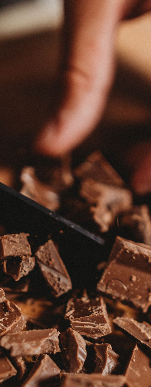 Close-up of hands chopping chocolate pieces
