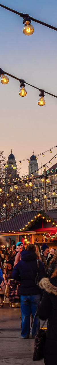 Crowded Christmas market at dusk with lights
