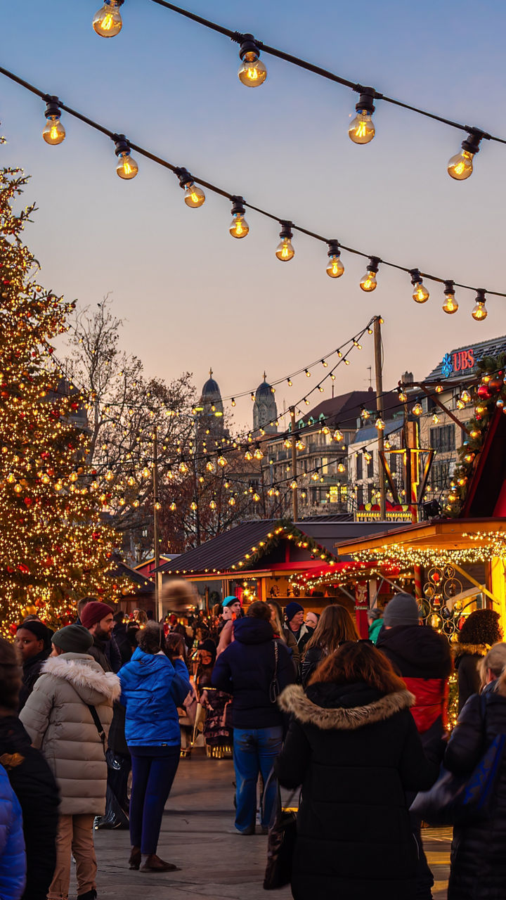 Crowded Christmas market at dusk with lights
