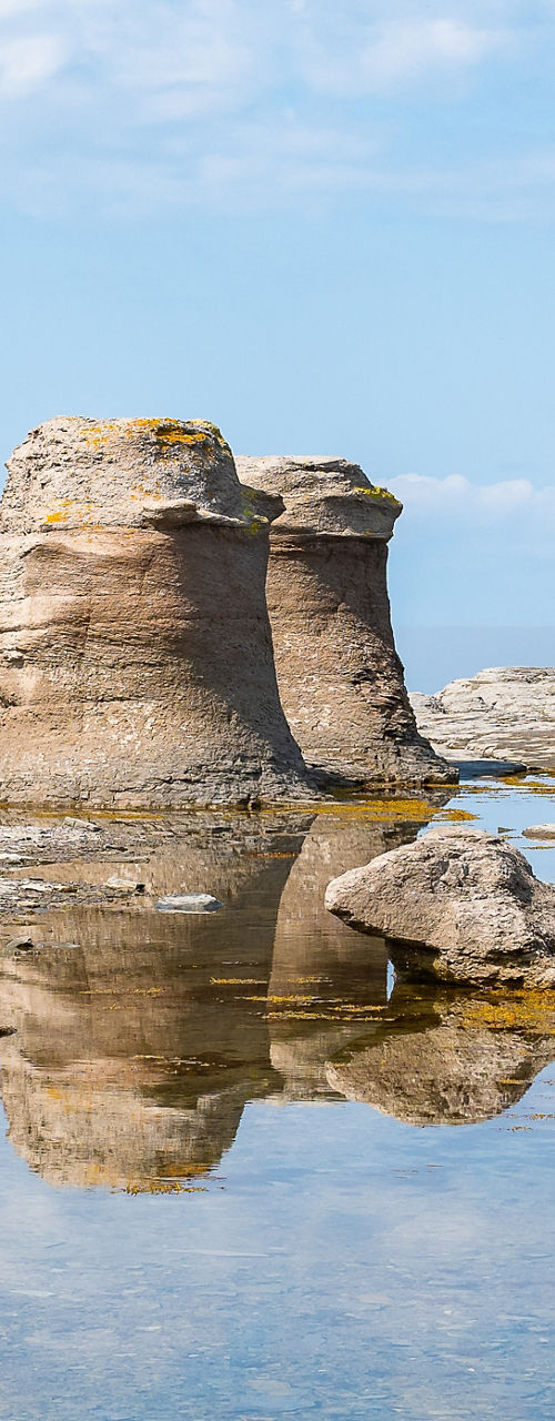 Rock formations by calm water under blue sky