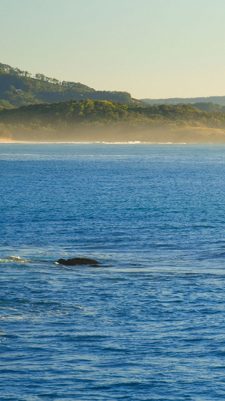 Scenic coastal view with surfers at sunrise