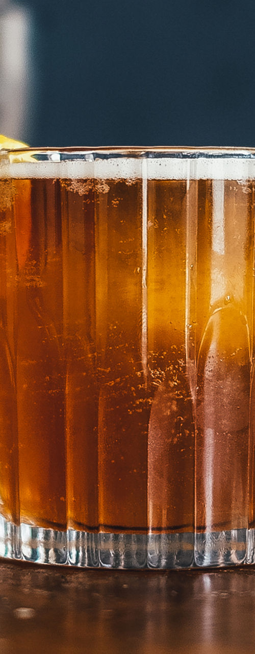 Whiskey cocktail with citrus garnish on bar