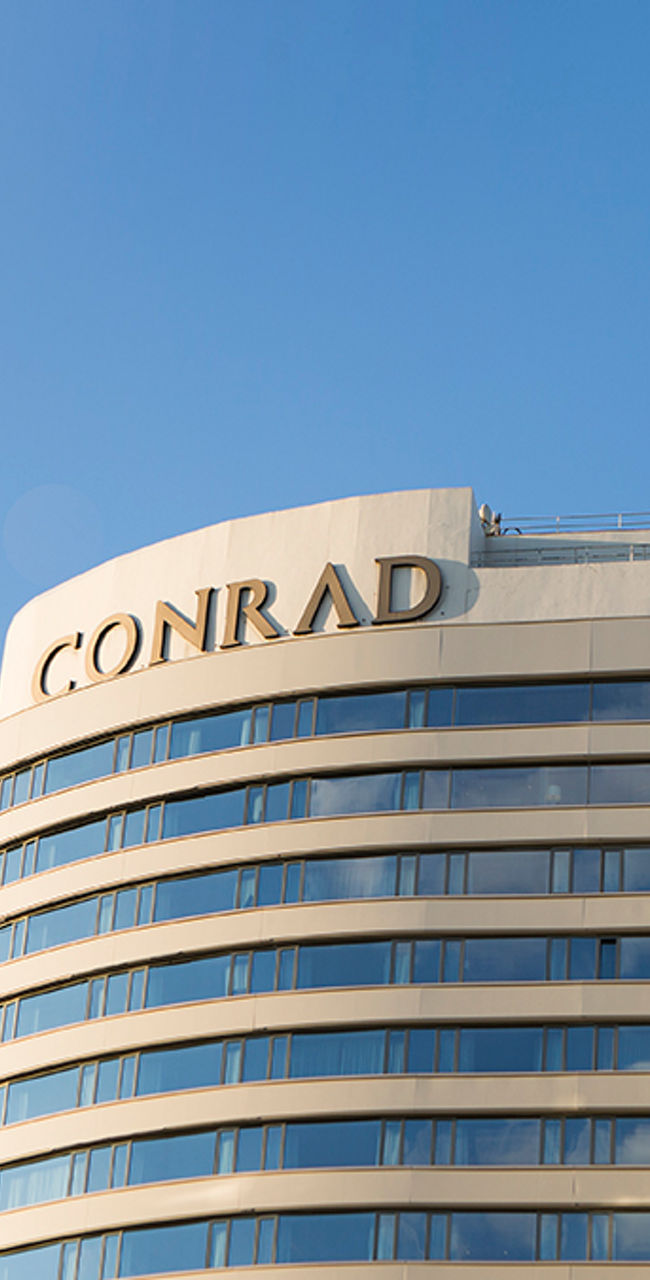 Modern Conrad hotel building under blue sky