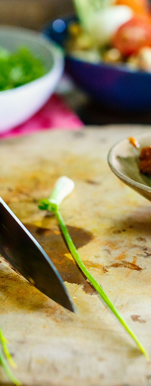 Chef slicing green onions on wooden board