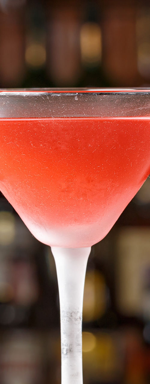 Red cocktail with lime garnish in bar setting