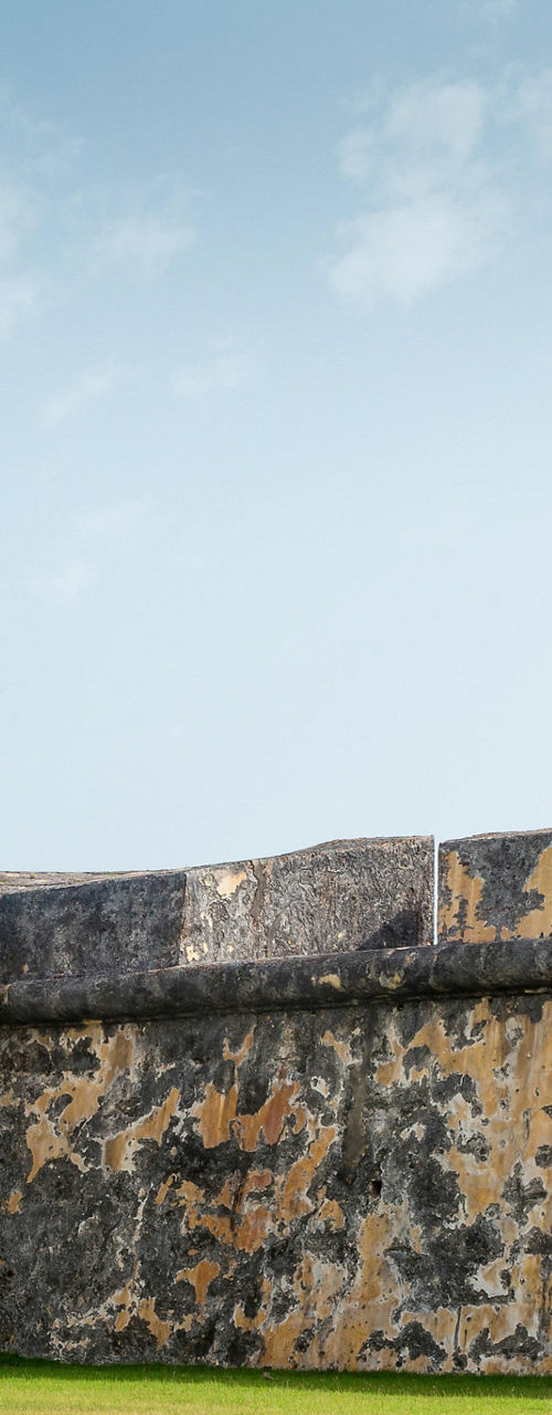 Historic lighthouse with flags and stone walls