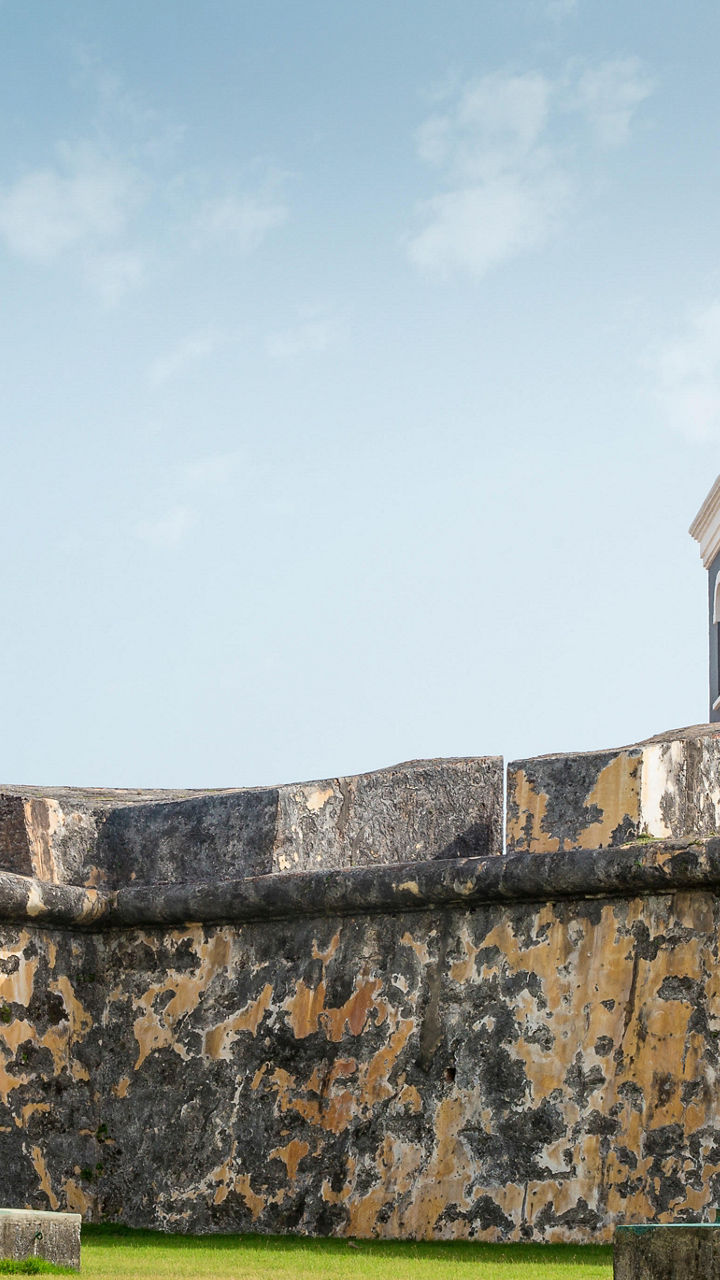 Historic lighthouse with flags and stone walls