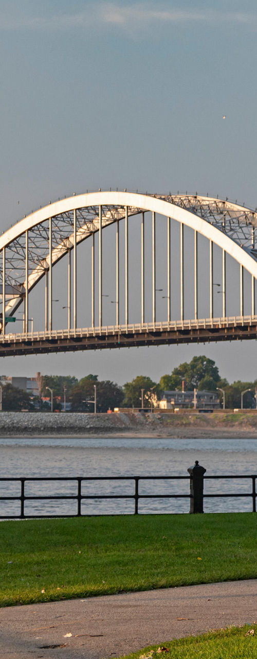 Cyclist near scenic arched bridge at sunset