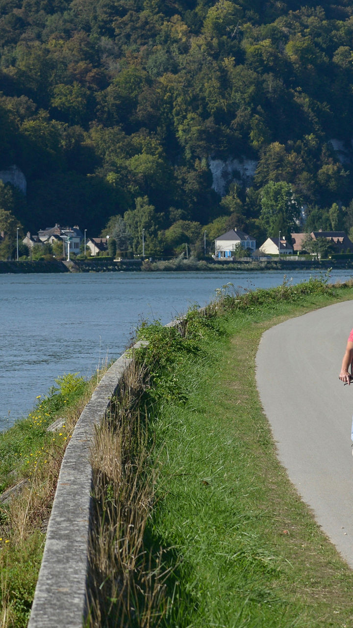 Couple cycling along scenic riverside path