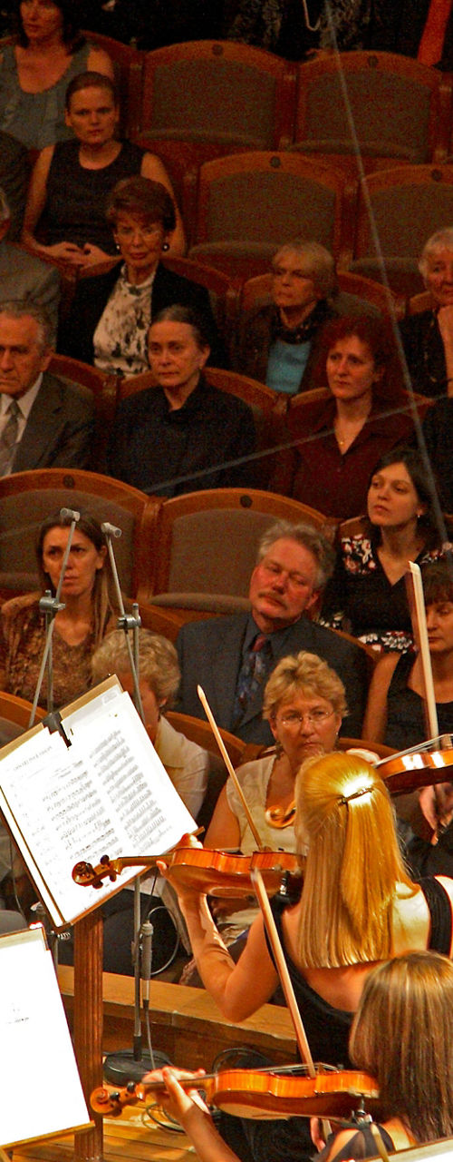 Conductor leading orchestra in concert hall