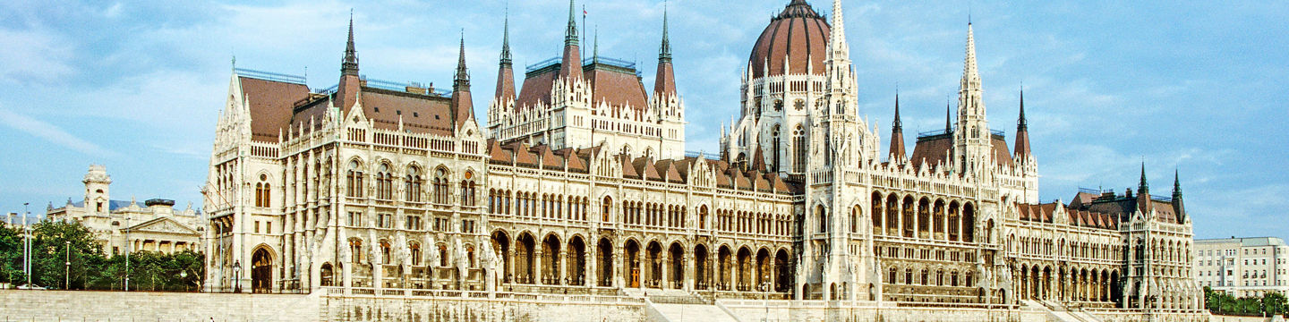 Historic riverside parliament building under blue sky