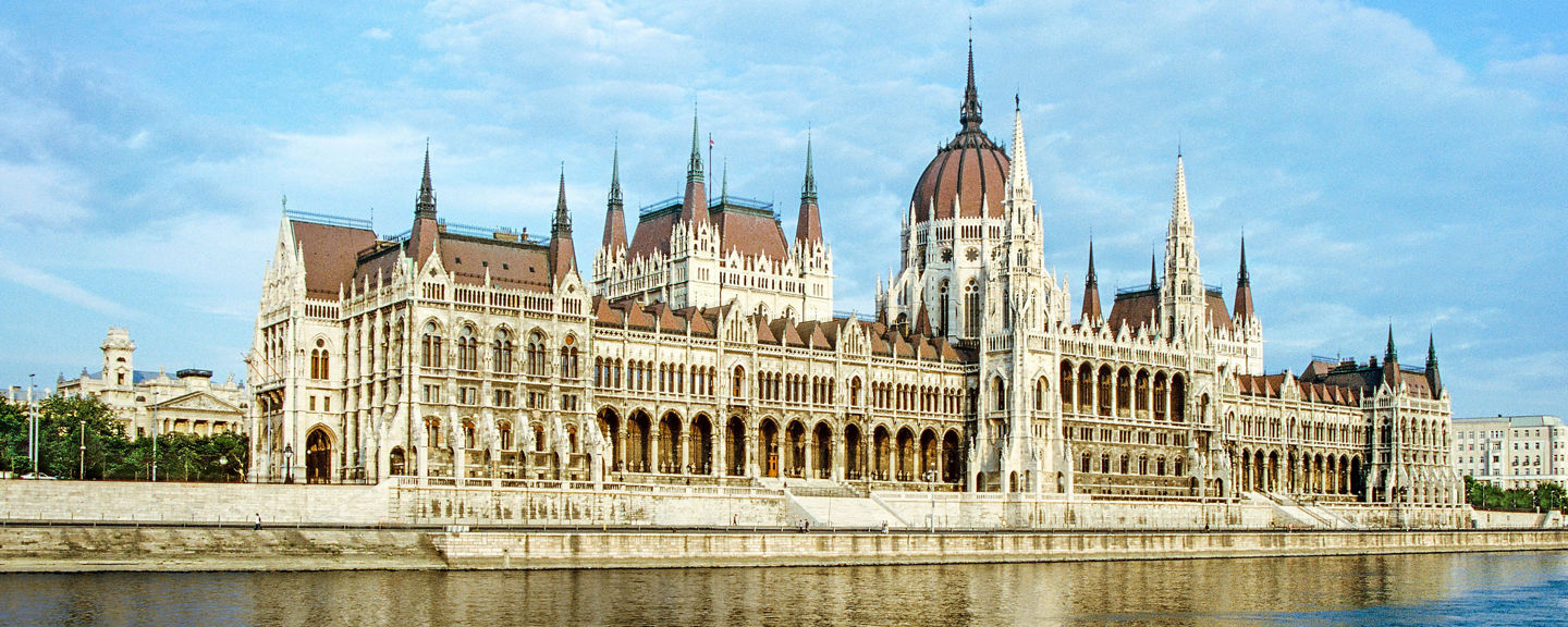 Historic riverside parliament building under blue sky