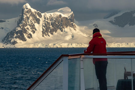 Person on deck overlooking snowy mountains