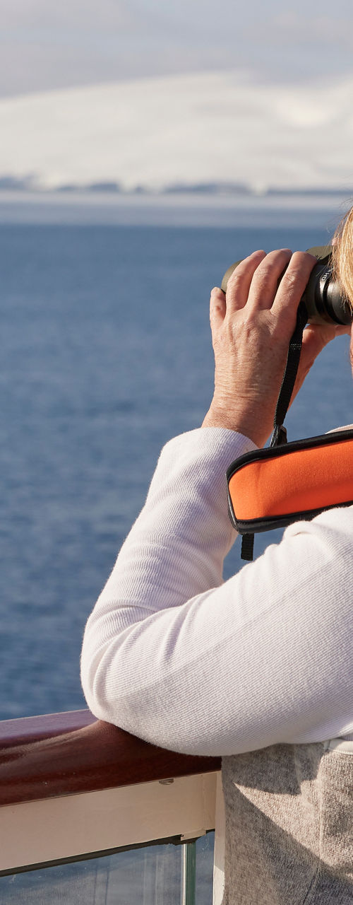 Woman observing icy landscape with binoculars