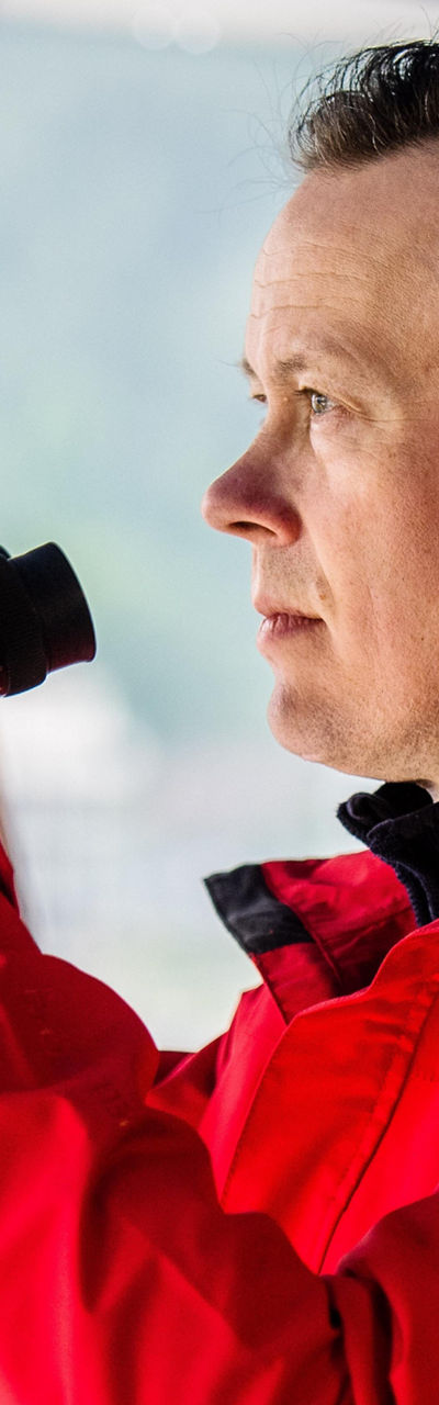 Man in red jacket using binoculars