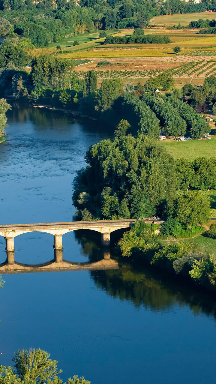 Scenic river with stone bridge and farmland