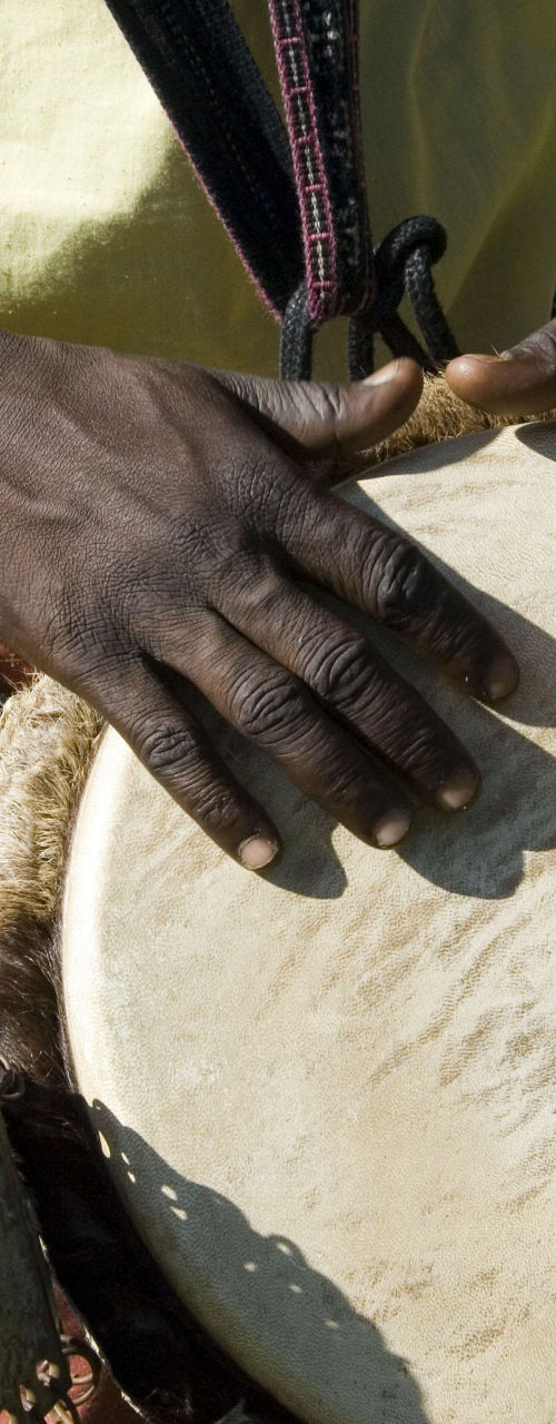 Close-up of hands playing a drum outdoors