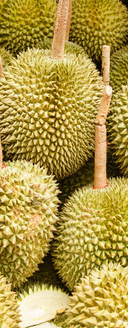Fresh durians stacked at outdoor market