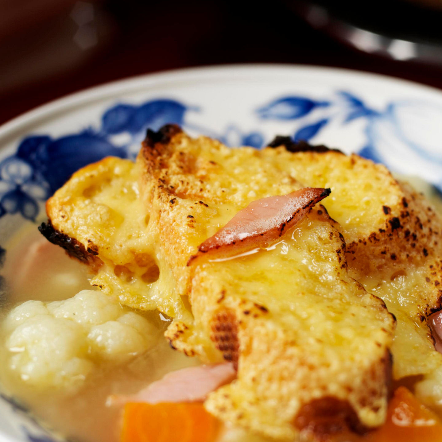 Rustic soup with bread topping in floral bowl