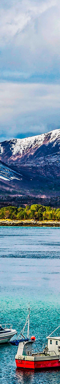 Snow-capped mountains with boats in fjord