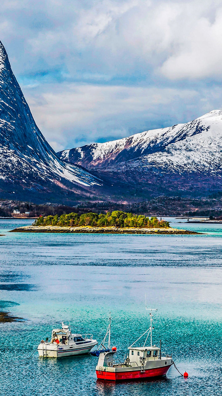 Snow-capped mountains with boats in fjord