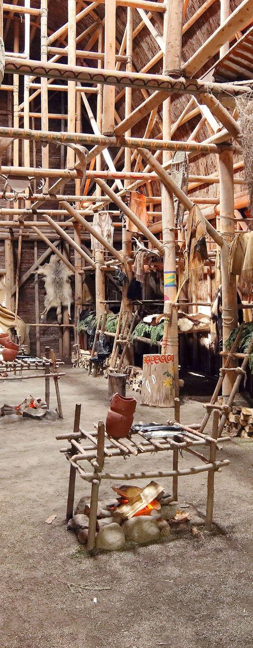 Traditional wooden longhouse interior with fire pit