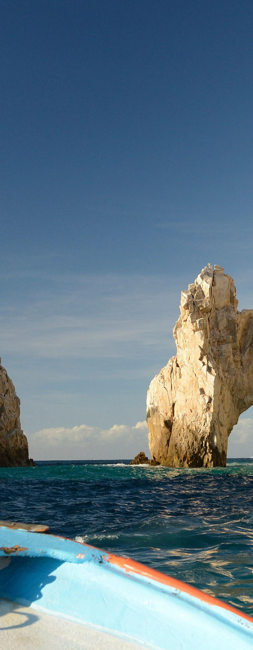 Boat approaching rocky arch in ocean