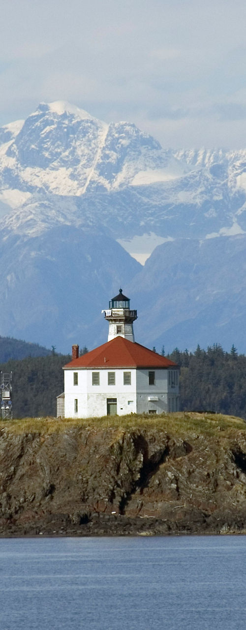 Scenic lighthouse on rocky island with mountains