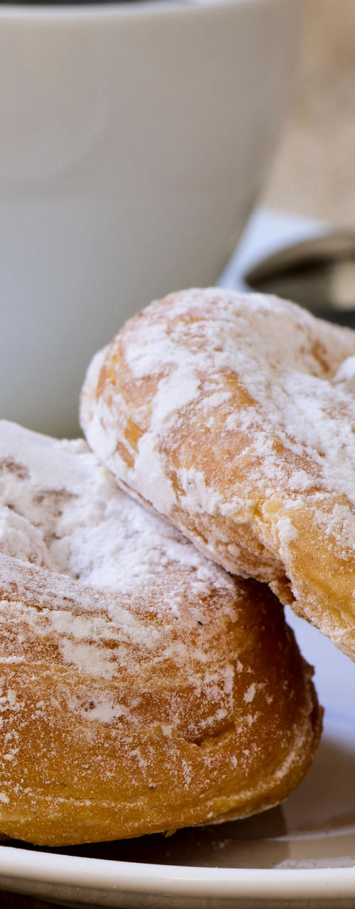 Powdered pastries with coffee on wooden table