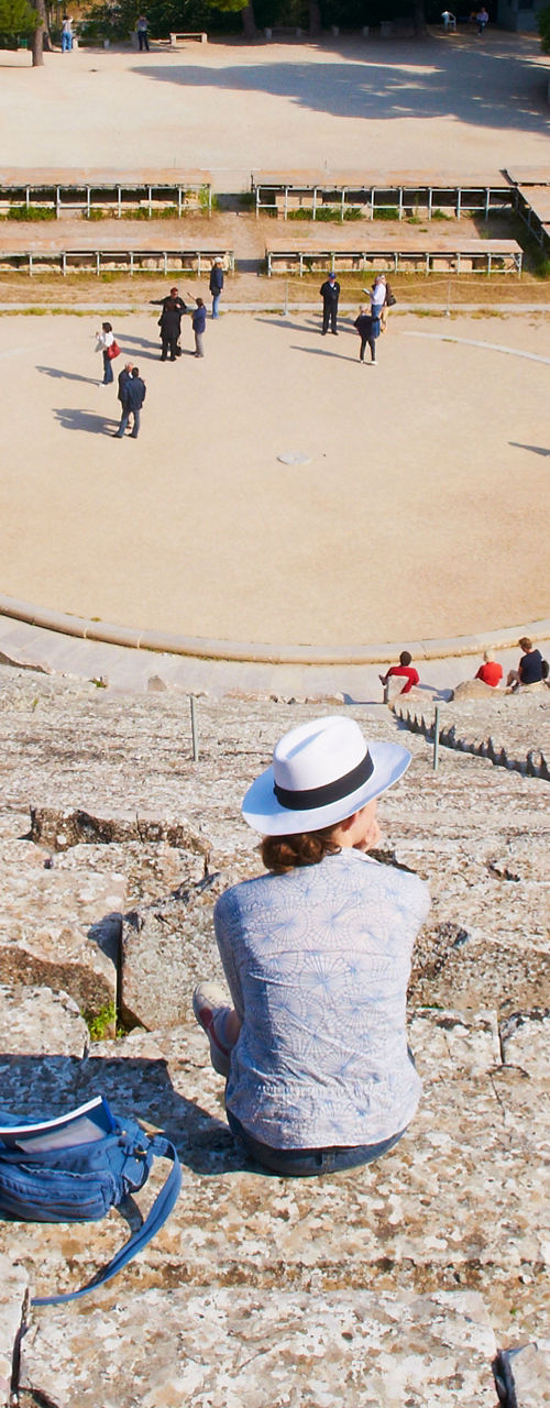 Woman sitting in ancient amphitheater ruins