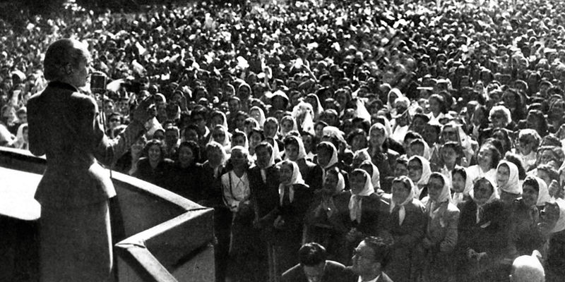 Woman addressing large outdoor crowd