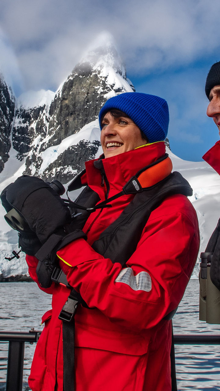 Two explorers in red jackets near iceberg