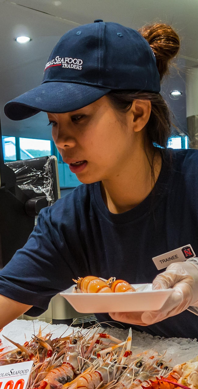 Seafood market staff arranging fresh lobsters