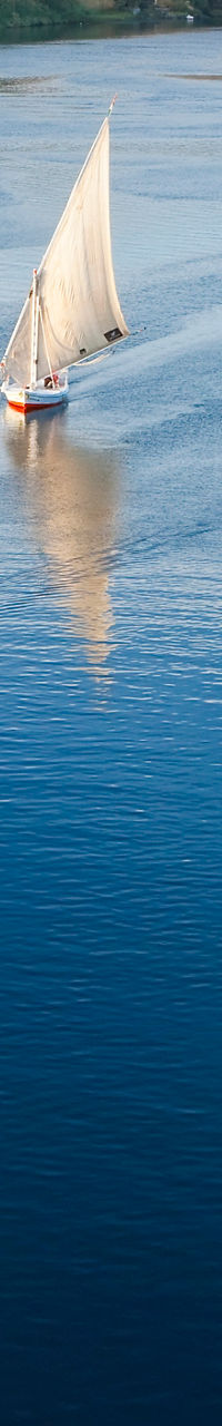 Sailboats on serene river with desert backdrop
