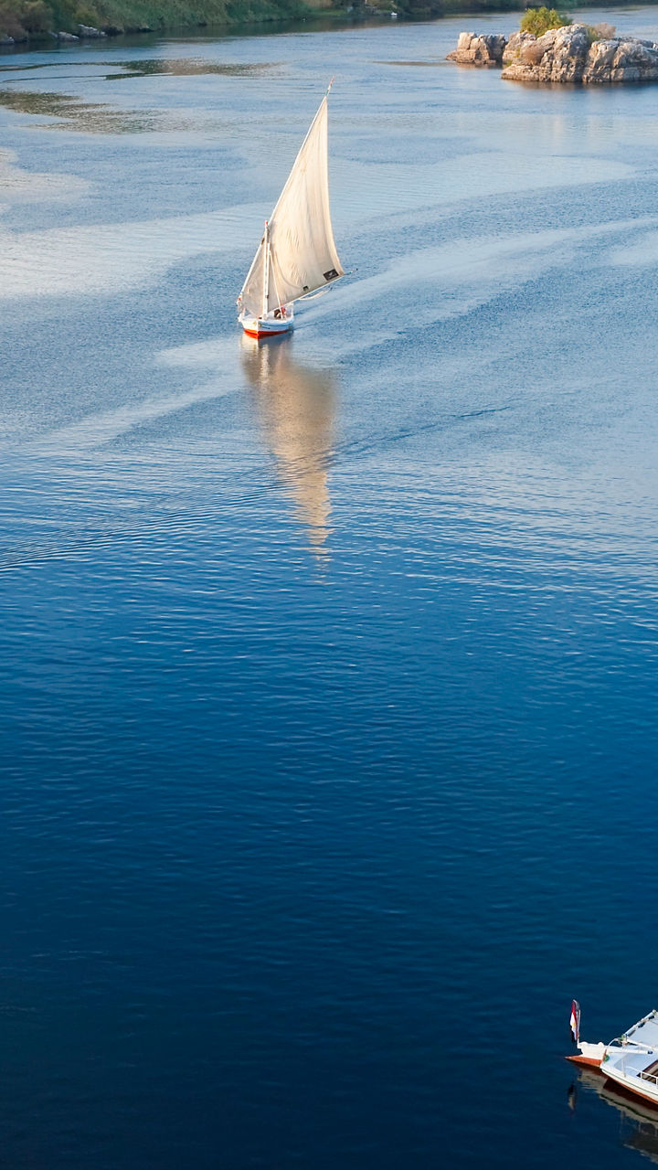 Sailboats on serene river with desert backdrop
