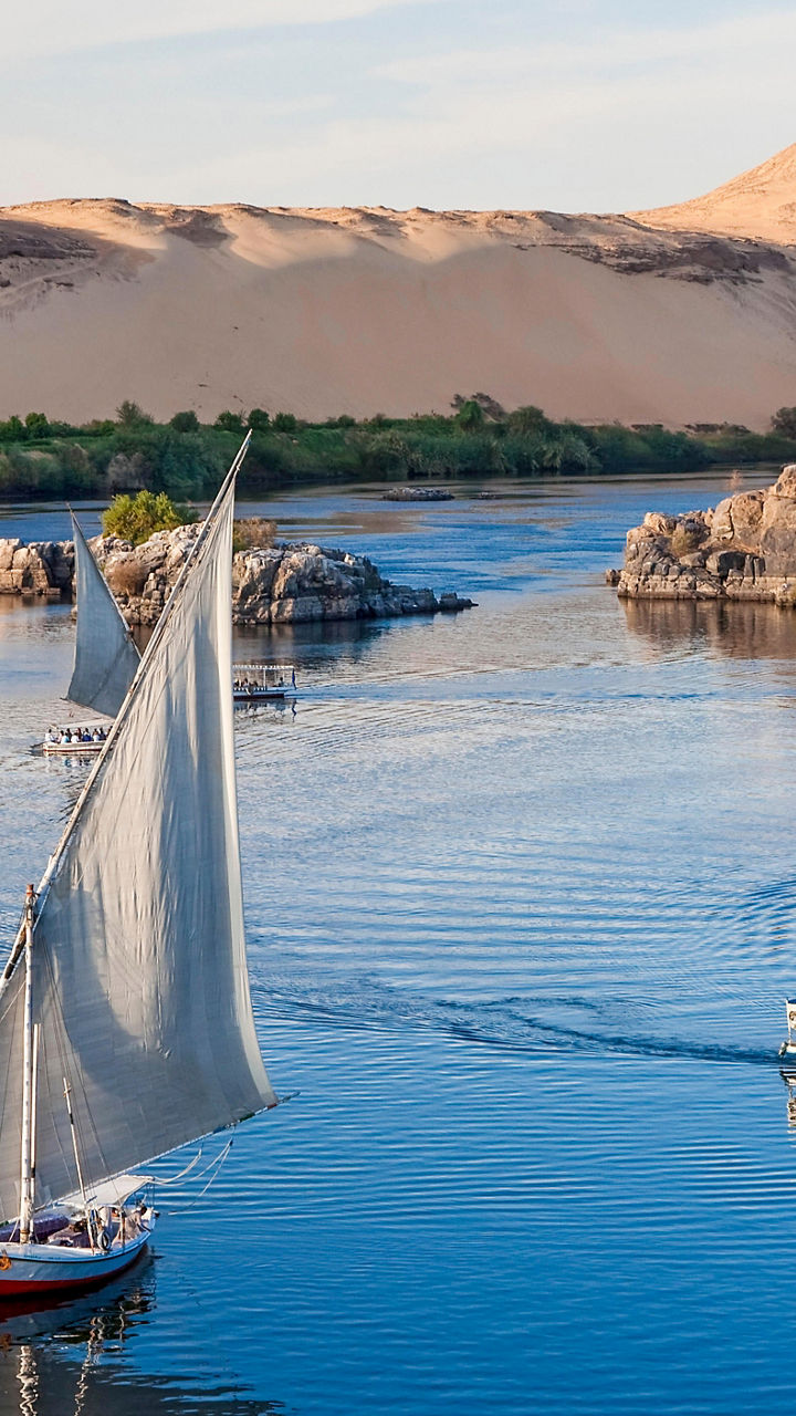 Sailboat on serene river with desert backdrop