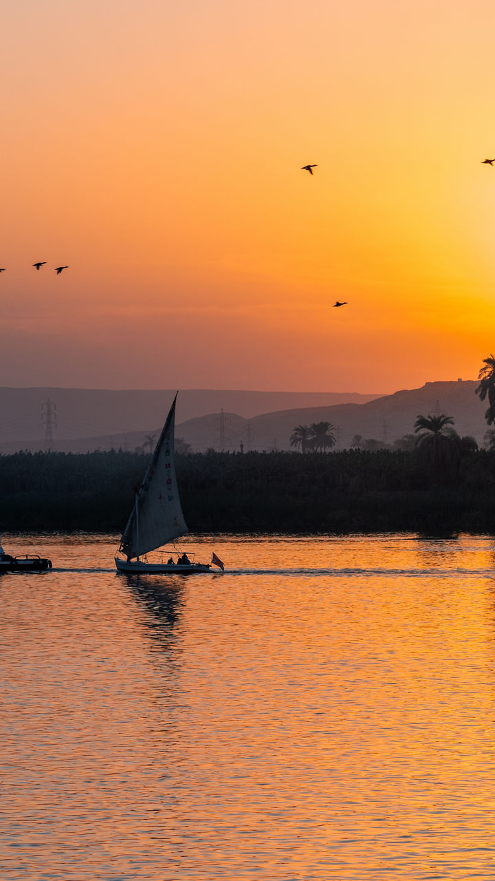 Sailboat on tranquil river at sunset