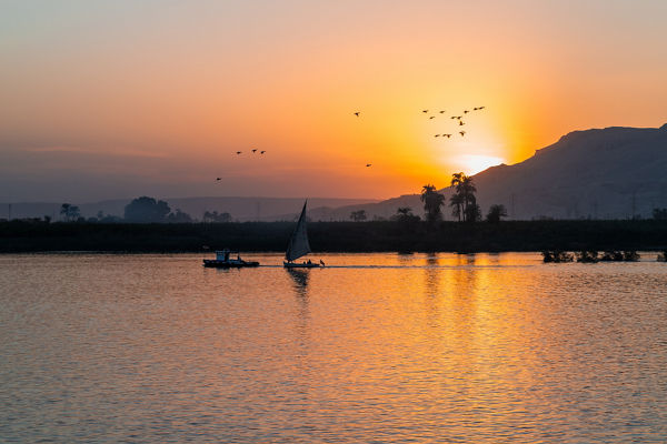 Sailboat on tranquil river at sunset