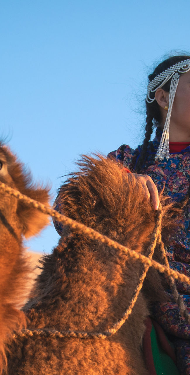 Person riding camels in desert landscape