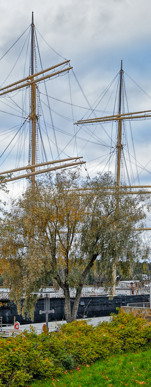 Maritime statue with tall ships in harbor