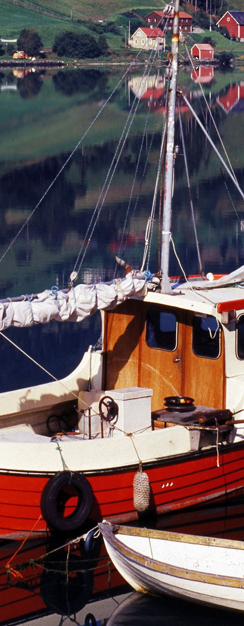 Red and white fishing boat on calm lake